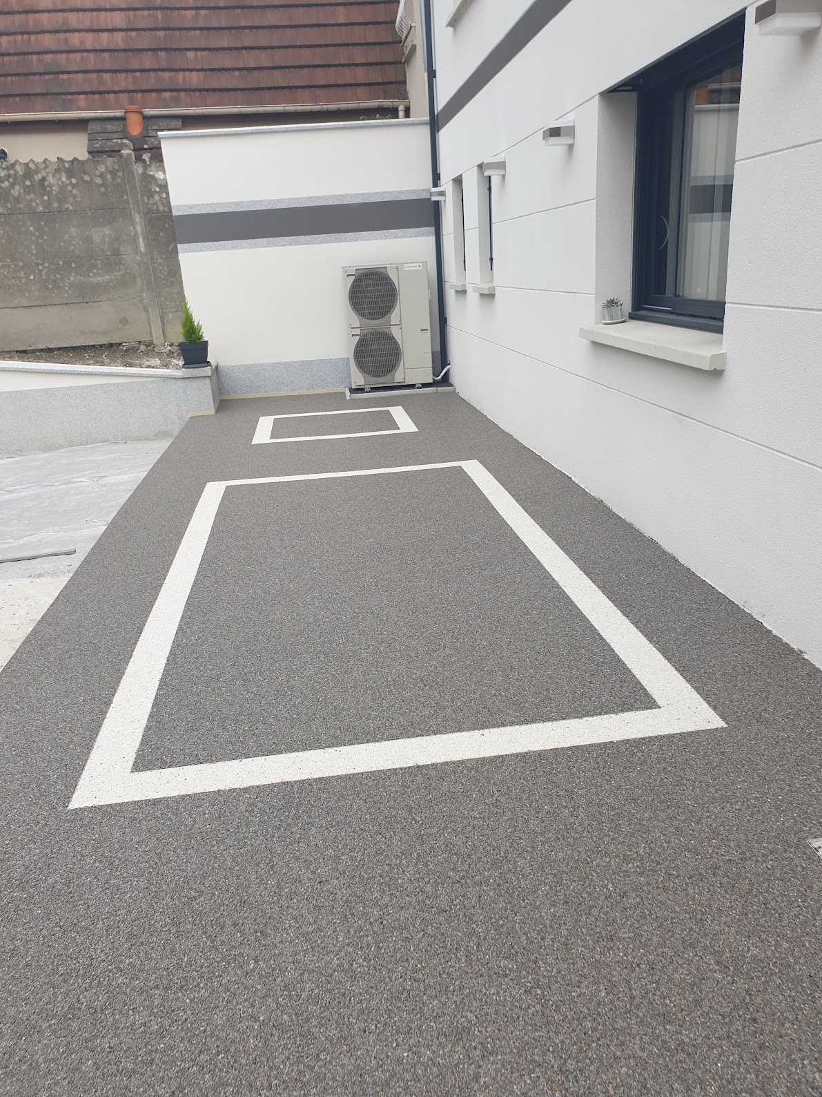 Allée d'une maison particulière en moquette de pierre bicolore, cadres clairs sur fond gris