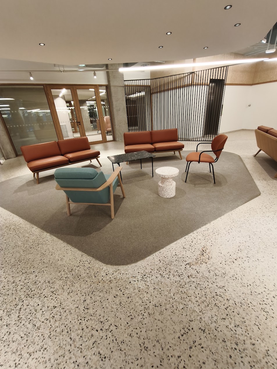 Espace détente de bureaux, tapis textile encastré dans un sol terrazzo